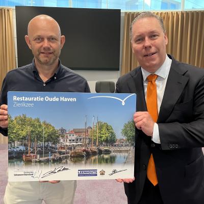 Wethouder en aannemer presenteren de ondertekening op een bord met daarop een foto van de Oude Haven